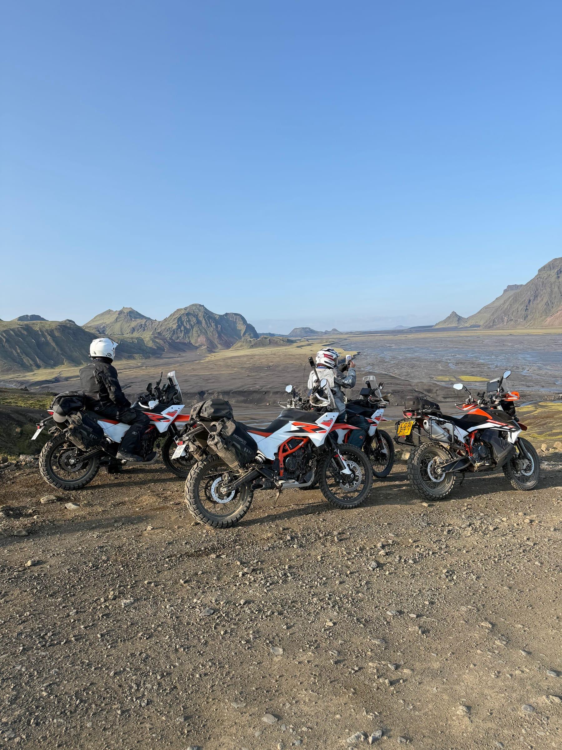 Riders on loaded adventure bikes overlooking a glacial river plain in the Icelandic highlands